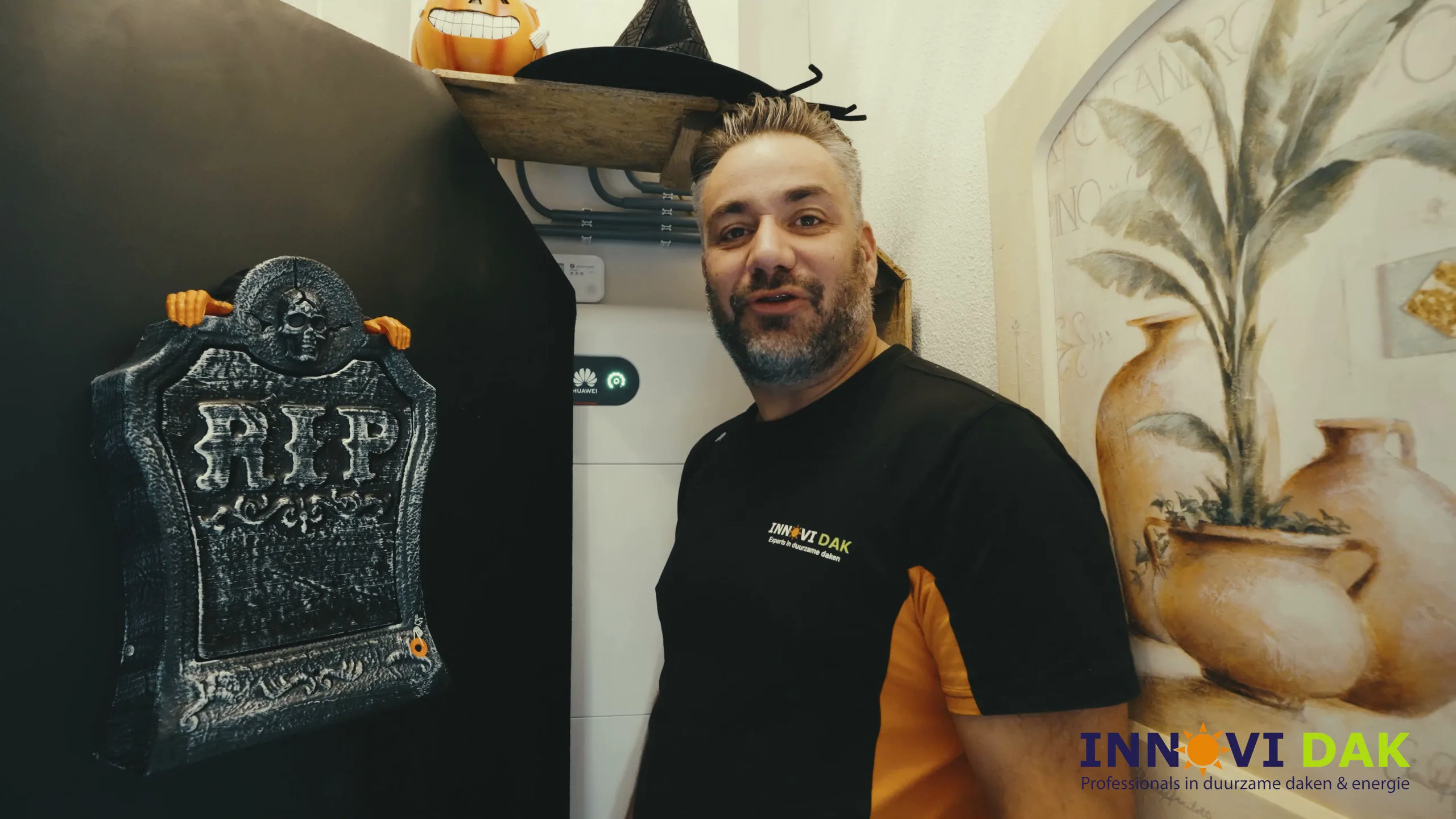 Monteur van Innovi Dak naast een thuisbatterij met Halloween-decoratie